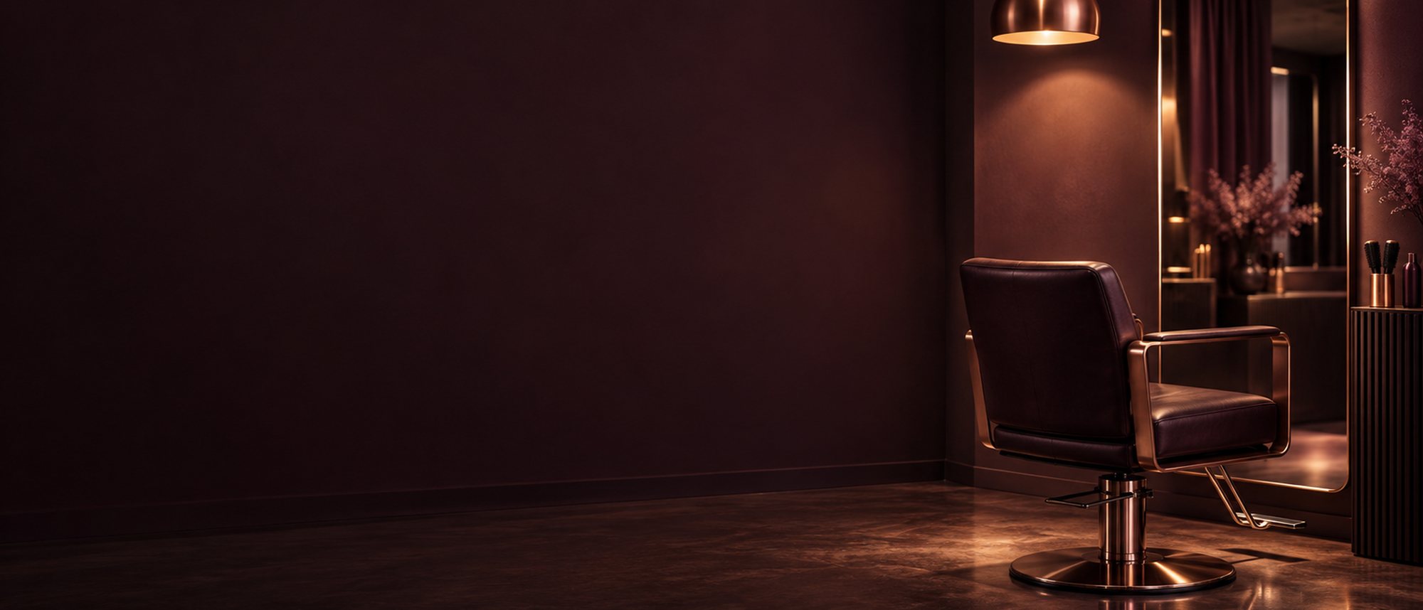One empty styling chair and a tall mirror under a single copper pendant lamp, in a salon with deep plum walls at dusk.